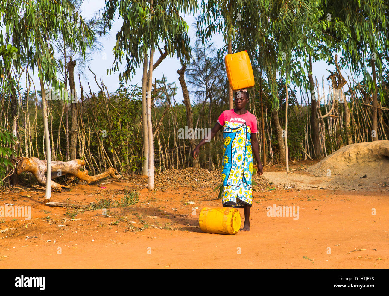 A young woman is carrying water from a nearest hydrant to her home. Malindi, Kenya. Stock Photo