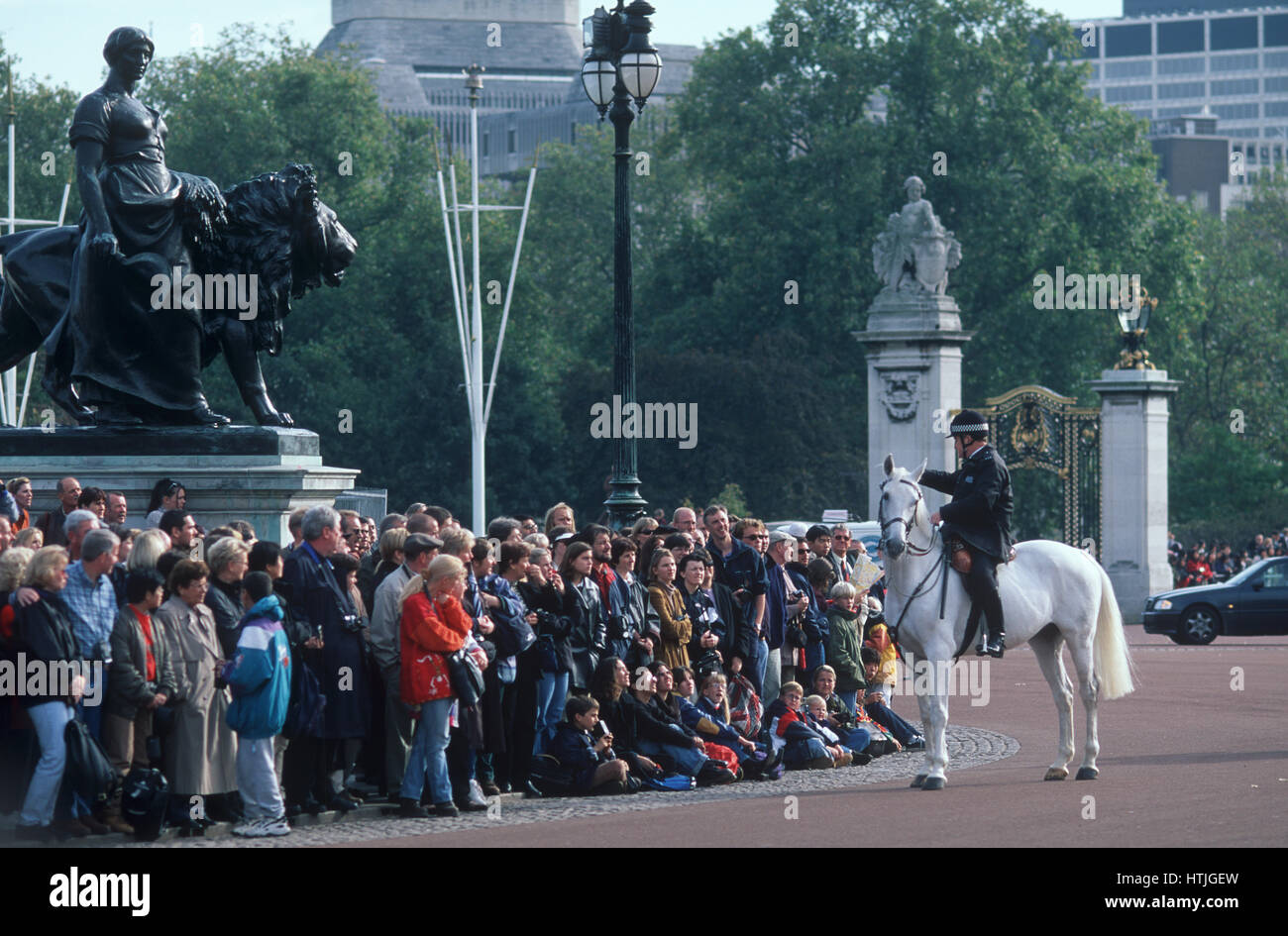 Crowd at Buckingham Palace for Changing of the guard. Bobbie on horse and Queen Victoria statue Stock Photo