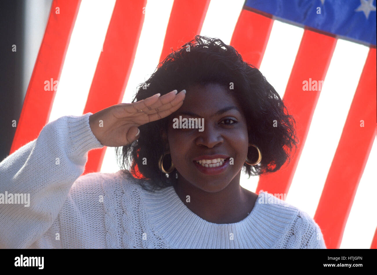 Woman salutes with flag as background Stock Photo