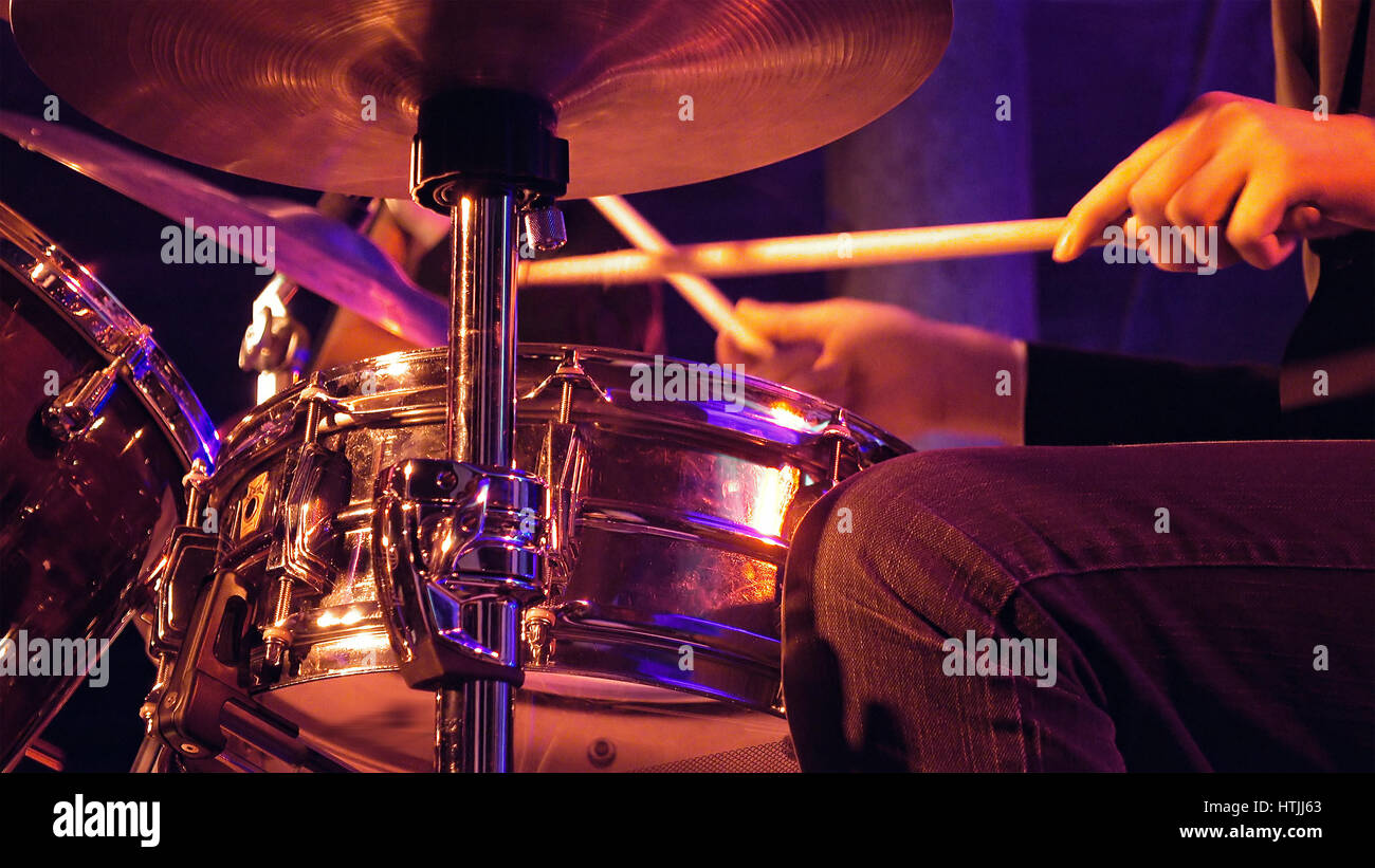 Drummer plays on drum set and cymbal with drumsticks on the stage. Jazz