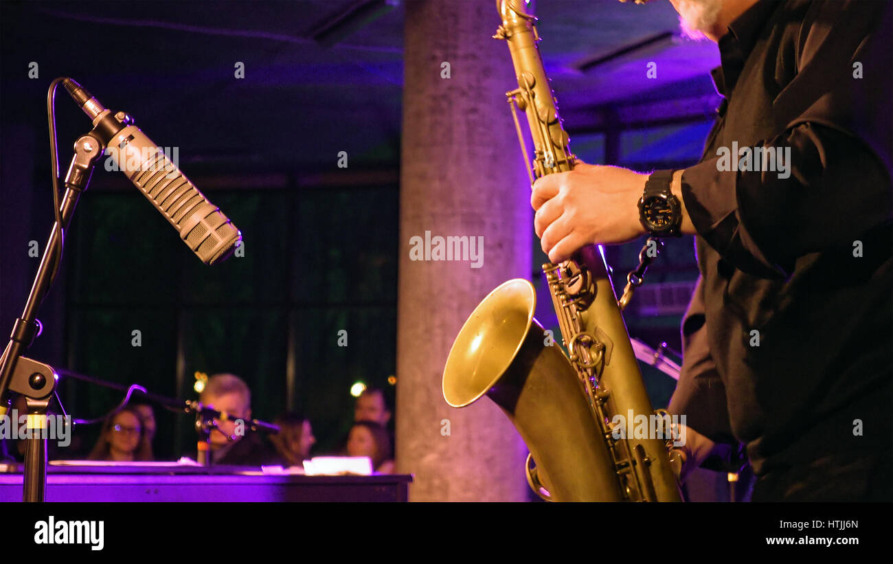 Saxophone player plays the saxophone on the stage with microphone. Jazz