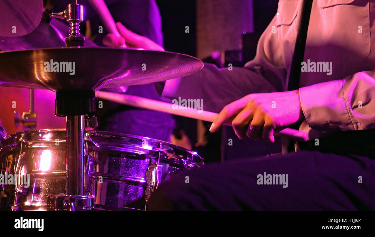 Drummer plays on drum set and cymbal with drumsticks on the stage. Jazz or rock concert performance entertainment. Close up shot with soft selective f Stock Photo
