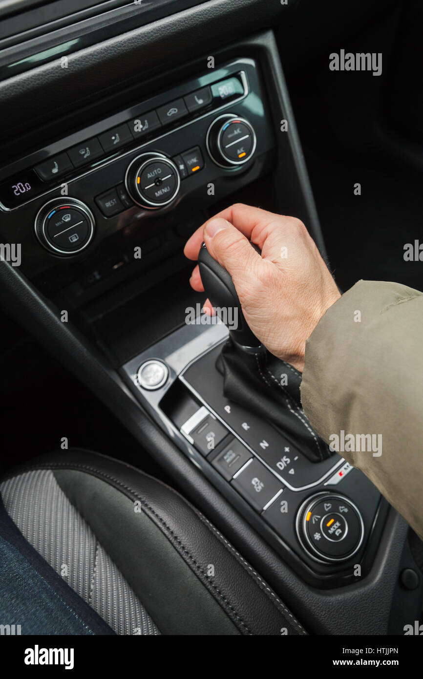 Driver hand holds gear lever of modern luxury car. Close up photo with selective focus Stock Photo