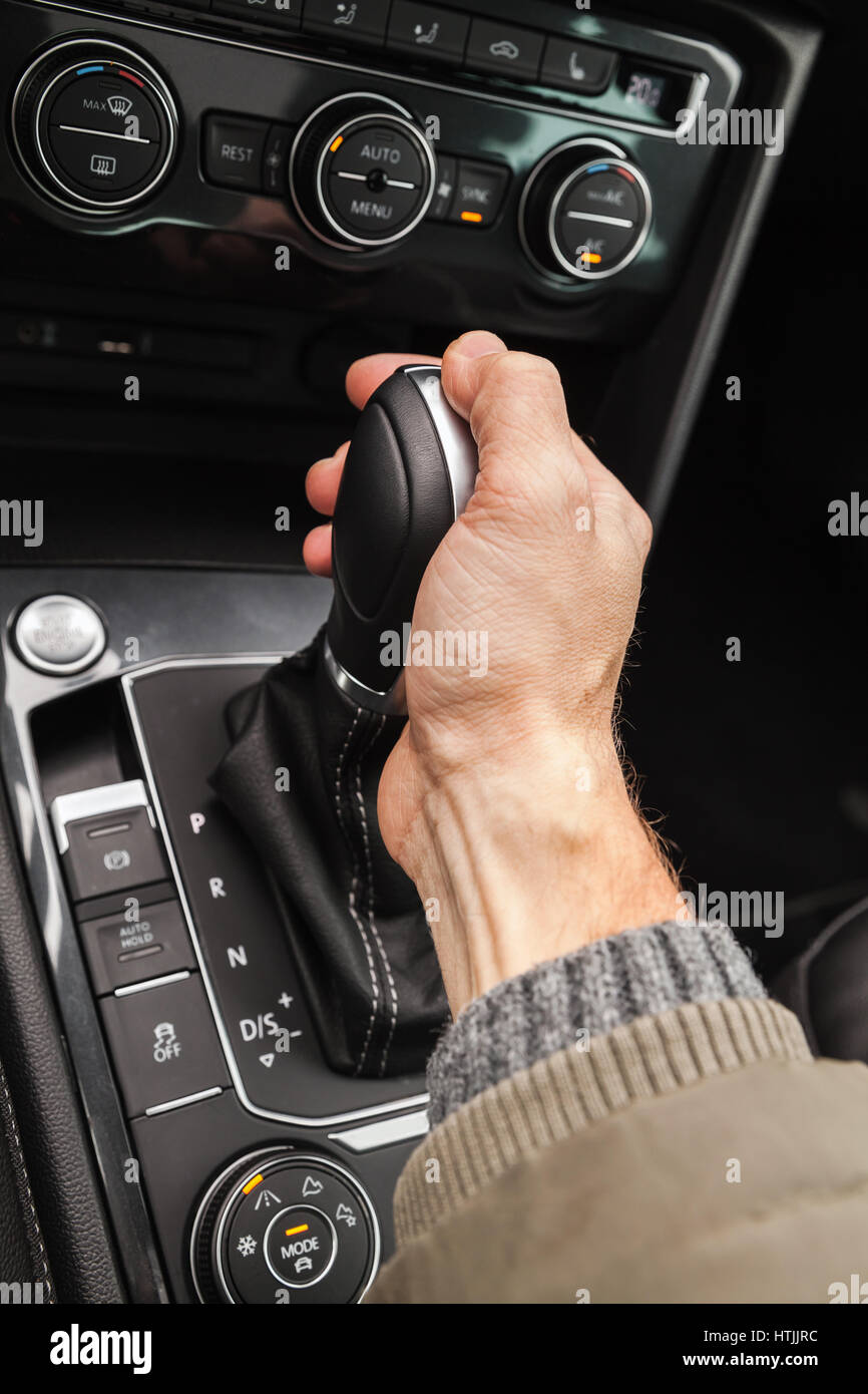 Driver hand holds gear lever of modern luxury crossover car. Close-up photo with selective focus Stock Photo