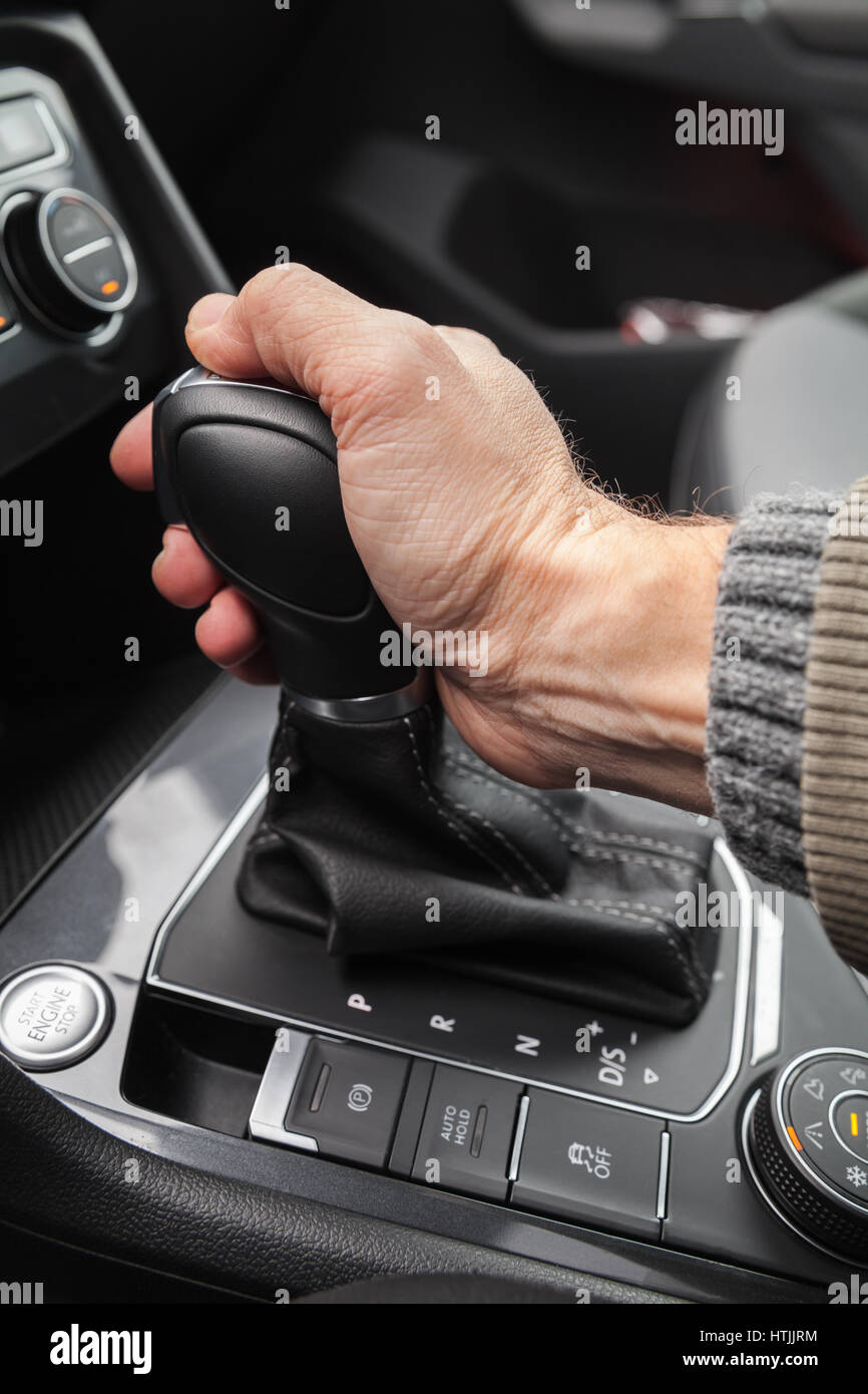 Driver hand holds gear lever of modern luxury crossover car. Closeup photo with selective focus Stock Photo