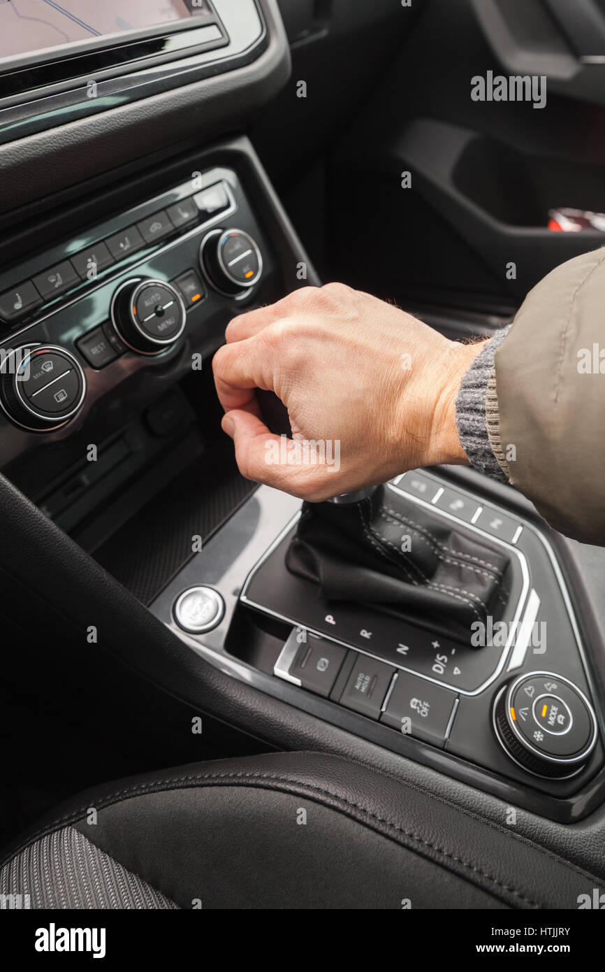 Driver hand holds gear lever of modern luxury crossover car. Close up photo with selective focus Stock Photo