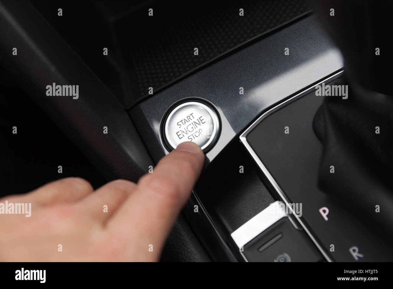 Driver hand pushes engine start stop button. Modern luxury crossover car interior details Stock Photo