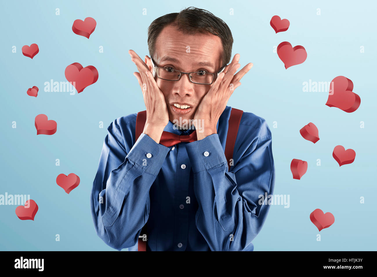 Young asian nerd man thinking with hand on face on blue background Stock Photo