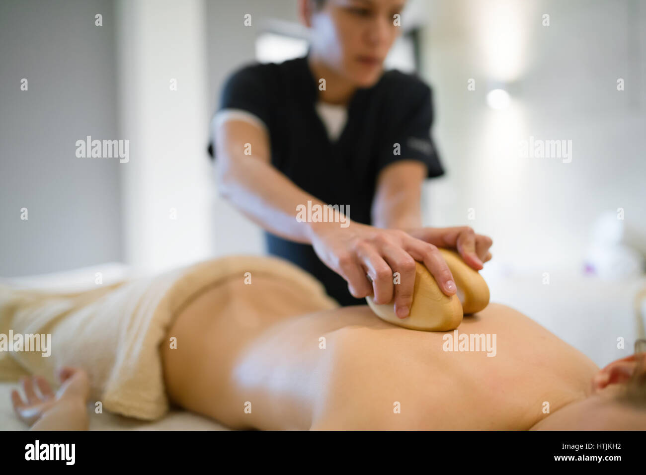 Masseur massaging female on bed while she relaxes Stock Photo
