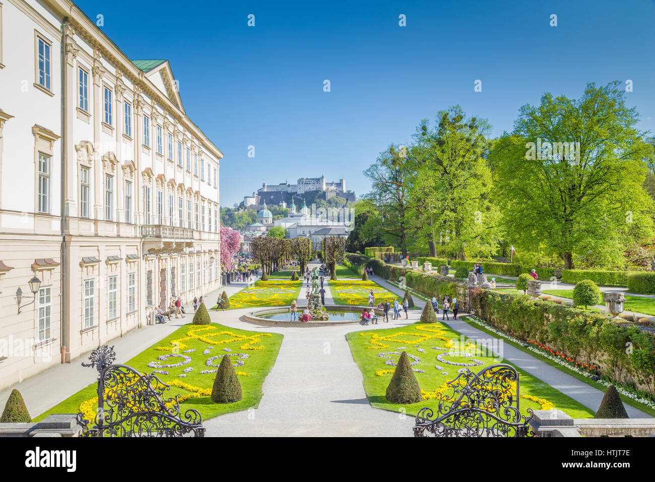 Tourists walking through famous Mirabell Gardens with famous Hohensalzburg Fortress in the background on a sunny day in summer, Salzburg, Austria Stock Photo