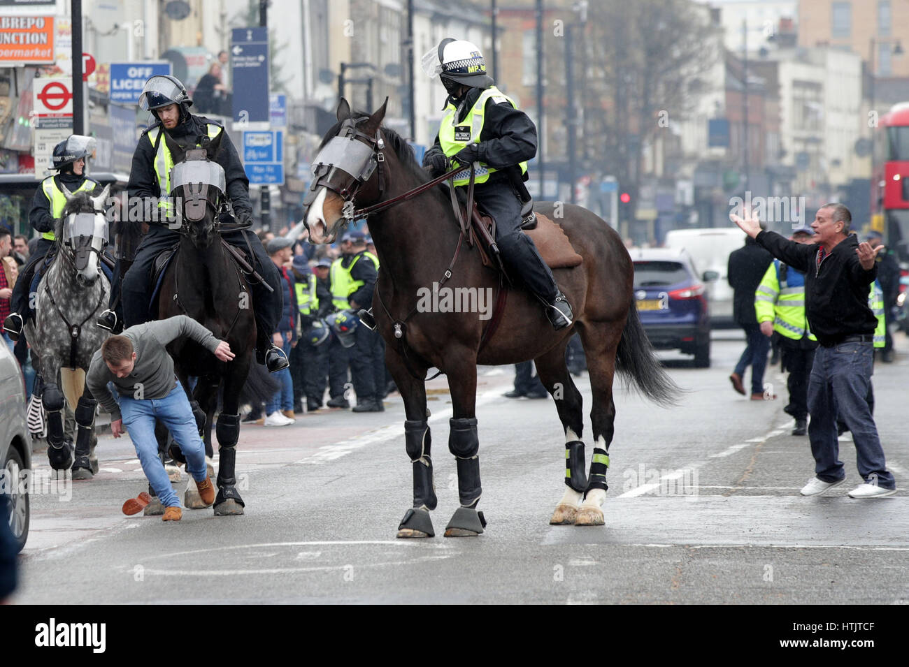 A football fan trips in front of a police horse prior to the Tottenham