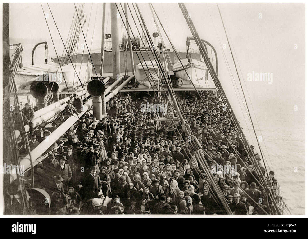 Immigrants to the United States on the deck of the German steamship SS Patricia operated by the Hamburg America Line, a German shipping company who’s transatlantic service was developed to carry German migrants to the United States. Photographed by Edwin Levick (1869-1929) in December 1906. Stock Photo