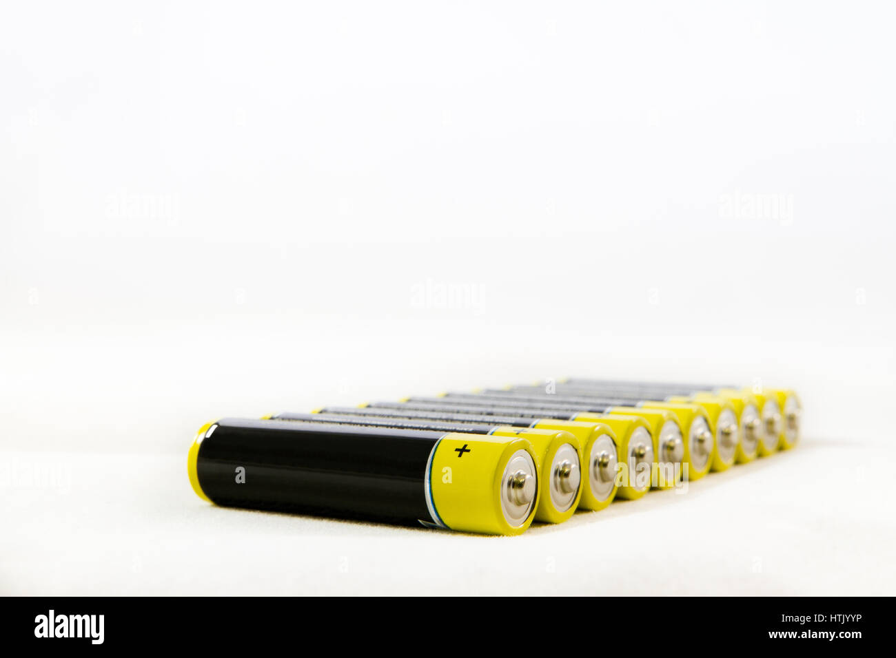 Diagonal row of yellow black AAA alkaline batteries isolated on a white