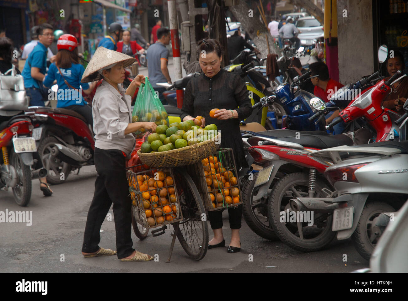 Woman carrying and selling fruit from her bike, Hanoi, Vietnam. Stock Photo
