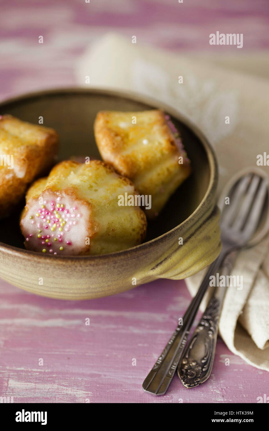 Traditional Polish babka - Easter mini cakes with icing and pink sprinkles. Stock Photo