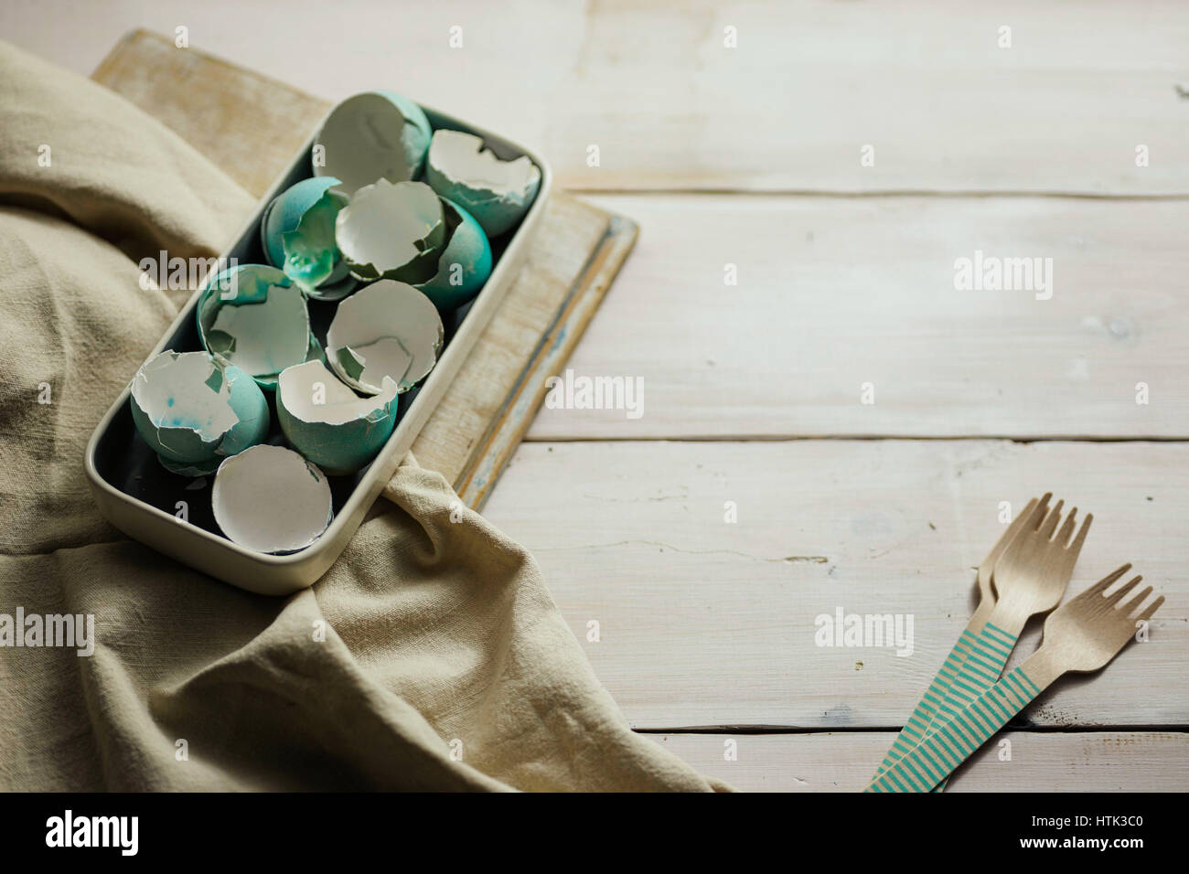 Plate full of blue tinted eggshells on white wooden table. Easter decoration. Stock Photo