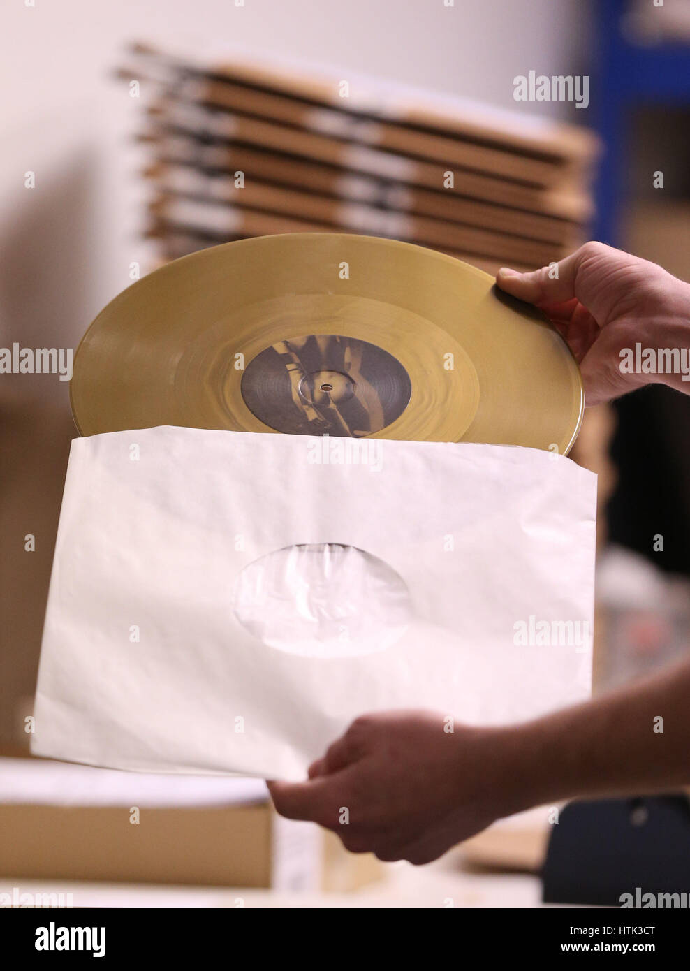 A packing operative places a gold coloured vinyl record into a sleeve at the Vinyl Factory, Hayes, Middlesex. Stock Photo