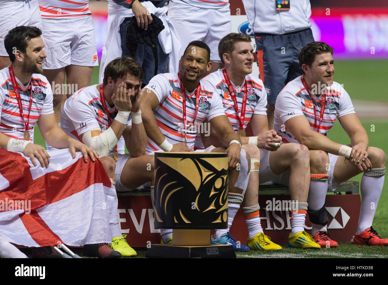 Vancouver, Canada. 12th Mar, 2017.  England players are sitting around their trophy, a First Nations Native carved bowl. Day 2-HSBC Canada Sevens Rugby Cup Final.BC Place Stadium. England wins the gold by defeating South Africa 19 -7. Credit: Gerry Rousseau/Alamy Live News Stock Photo