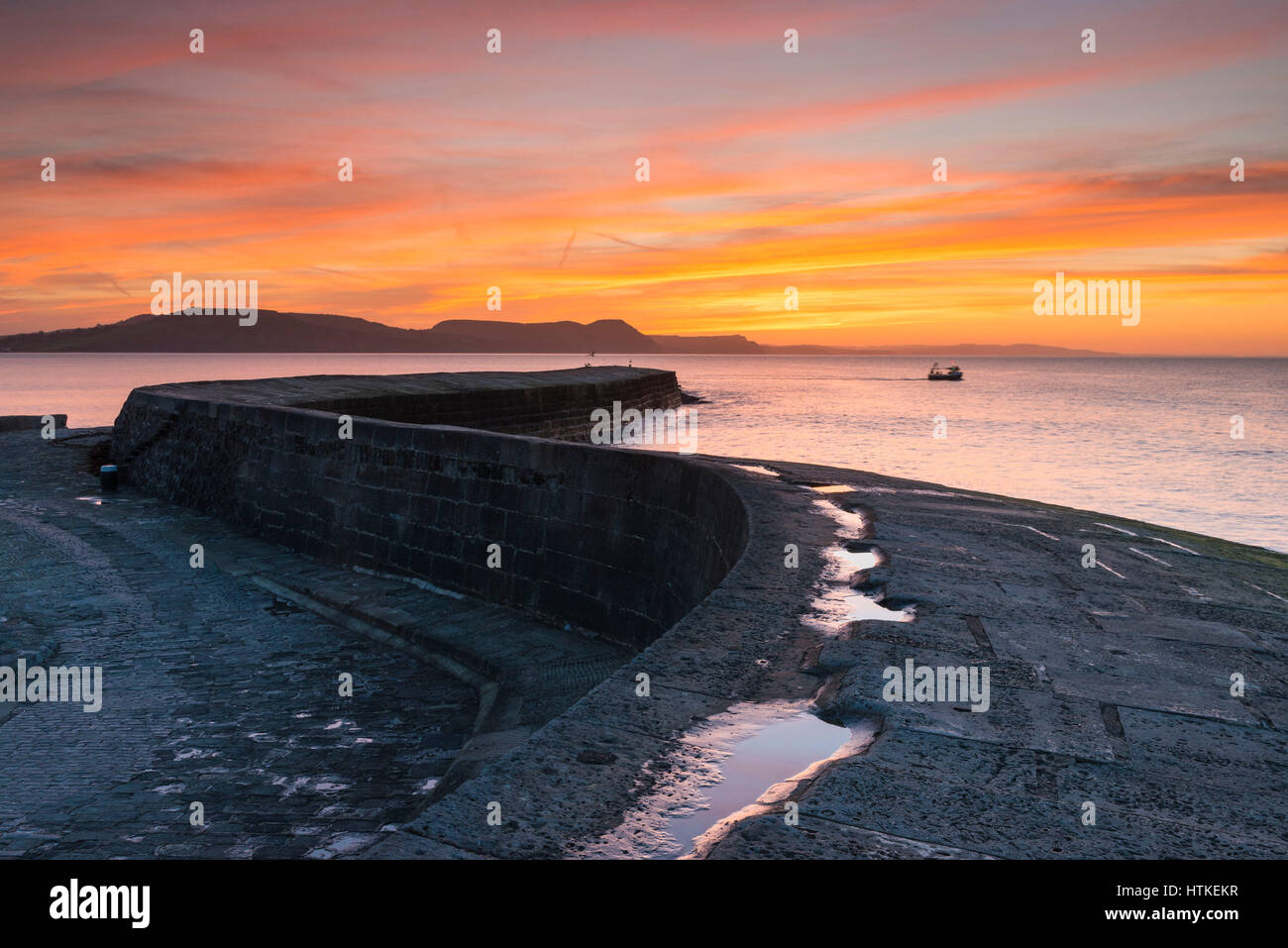 Lyme Regis, Dorset, UK.  13th March 2017.  UK Weather. A glorious spring sunrise viewed from the historic Cobb harbour wall at the seaside resort of Lyme Regis on the Dorset Jurassic Coast.  Photo by Graham Hunt/Alamy Live News Stock Photo