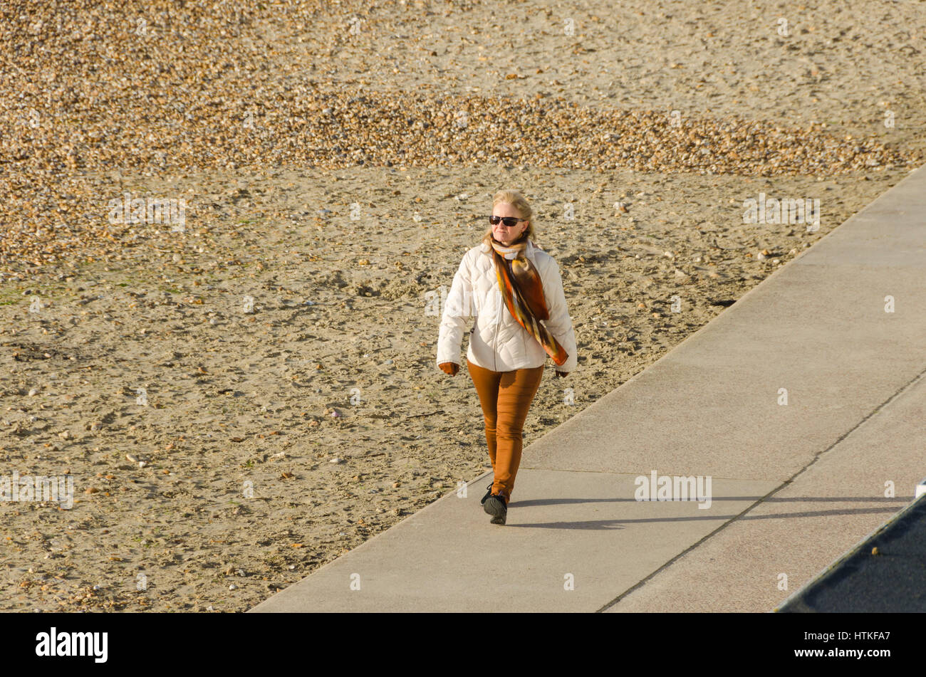 Lyme Regis, Dorset, UK.  13th March 2017.  UK Weather. A woman enjoying the beautiful warm spring sunshine and blues skies during the morning at the seaside resort of Lyme Regis on the Dorset Jurassic Coast.  Photo by Graham Hunt/Alamy Live News Stock Photo
