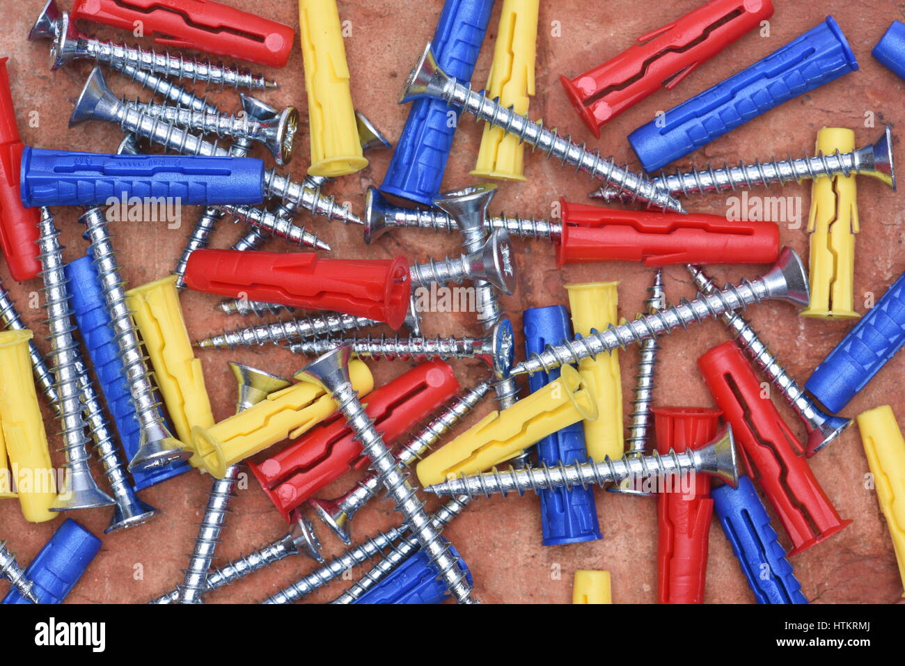 Plastic Dowels ans Screws on Red Brick Background Top View Stock Photo