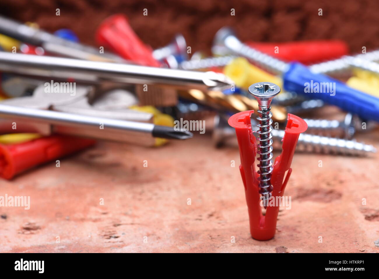 Screws plasctic dowels and tool on brick background close-up Stock Photo
