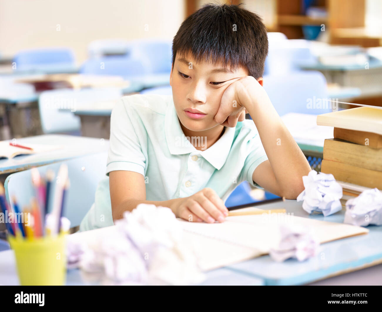 frustrated asian pupil sitting at desk dazing Stock Photo
