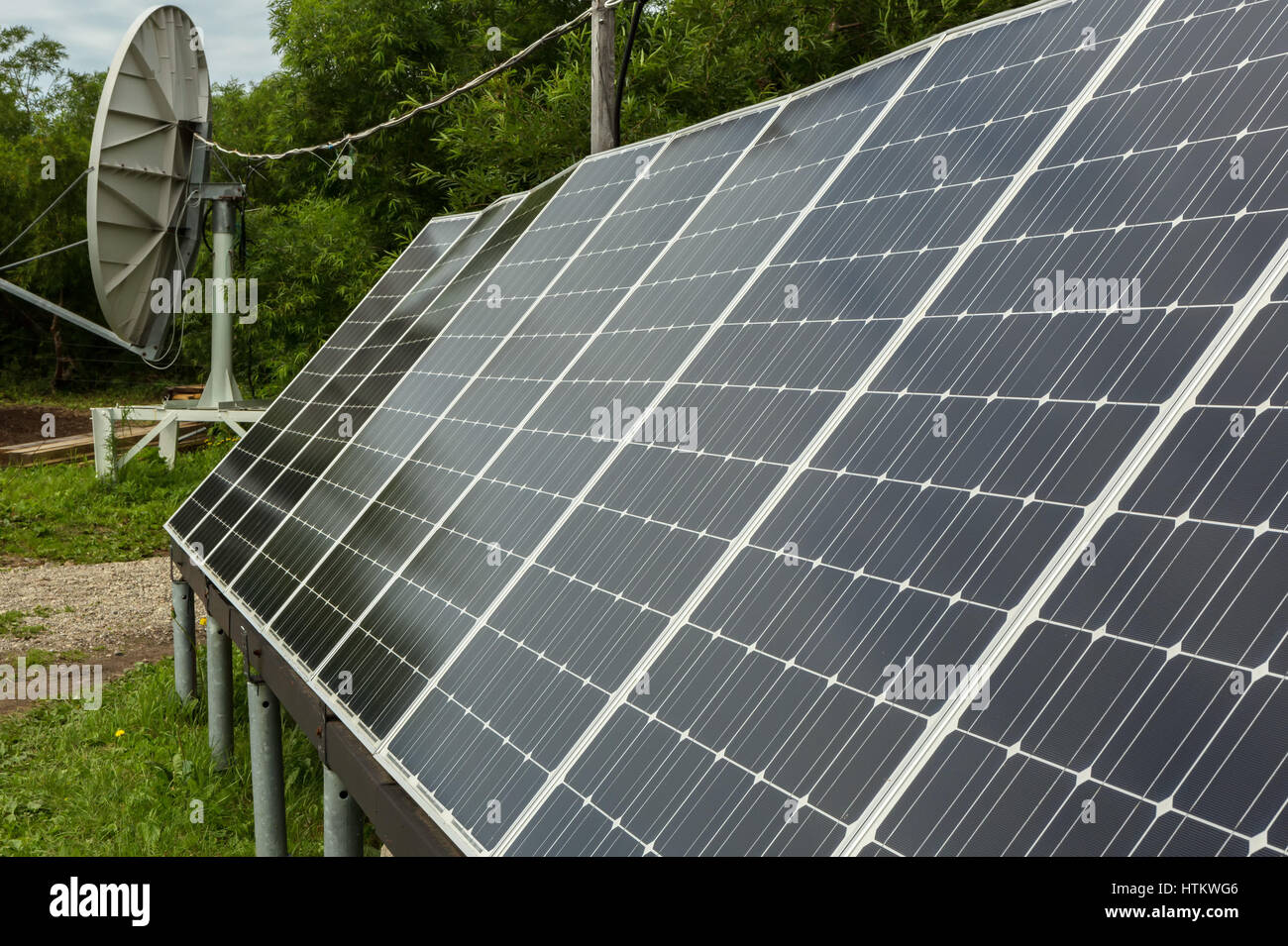 Solar panels and satellite dish for energy and communication in suburbs. Stock Photo