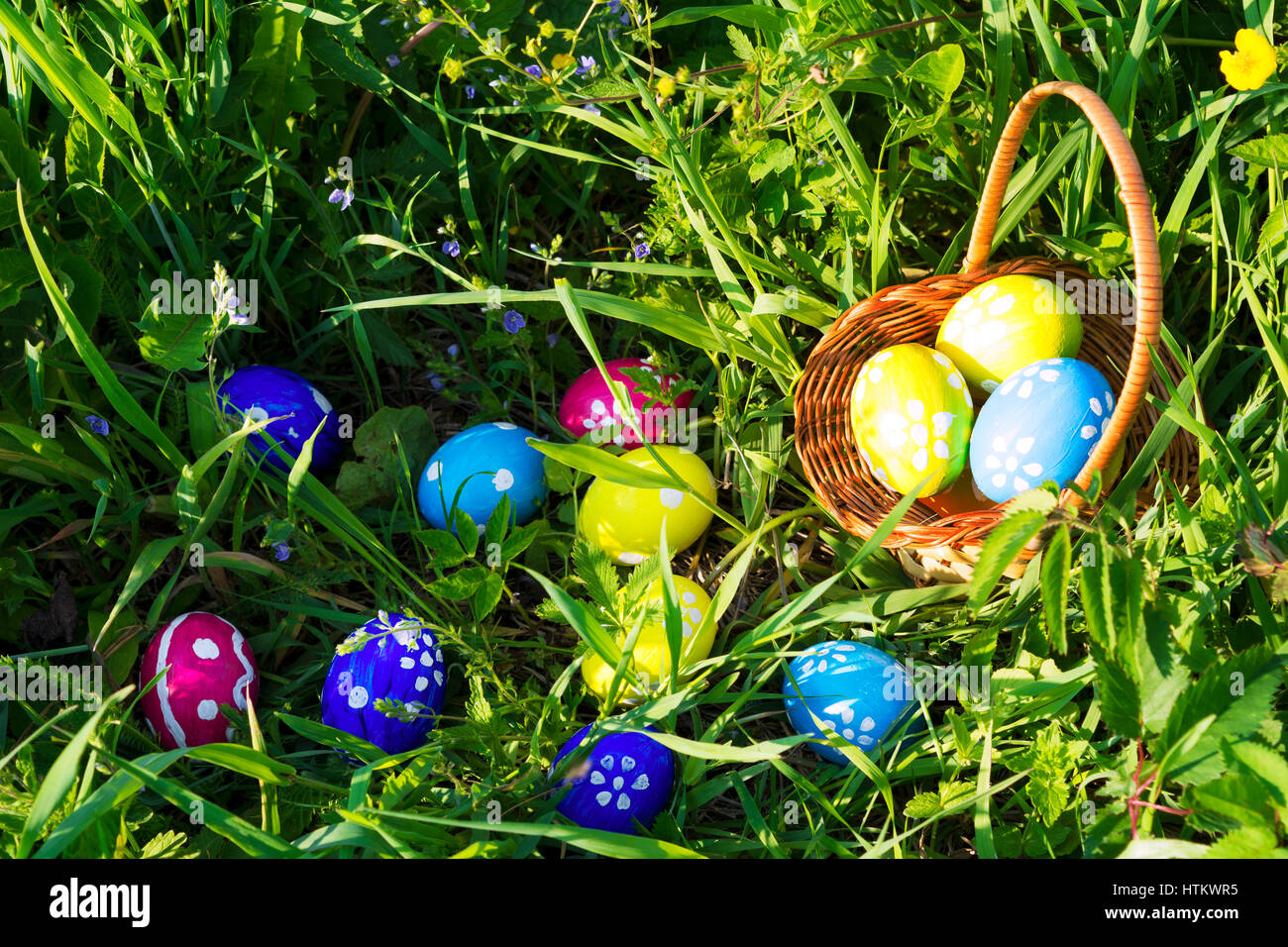 Easter background with hand painted eggs and wicker basket in green grass. Happy Easter greeting card or invitation. Stock Photo