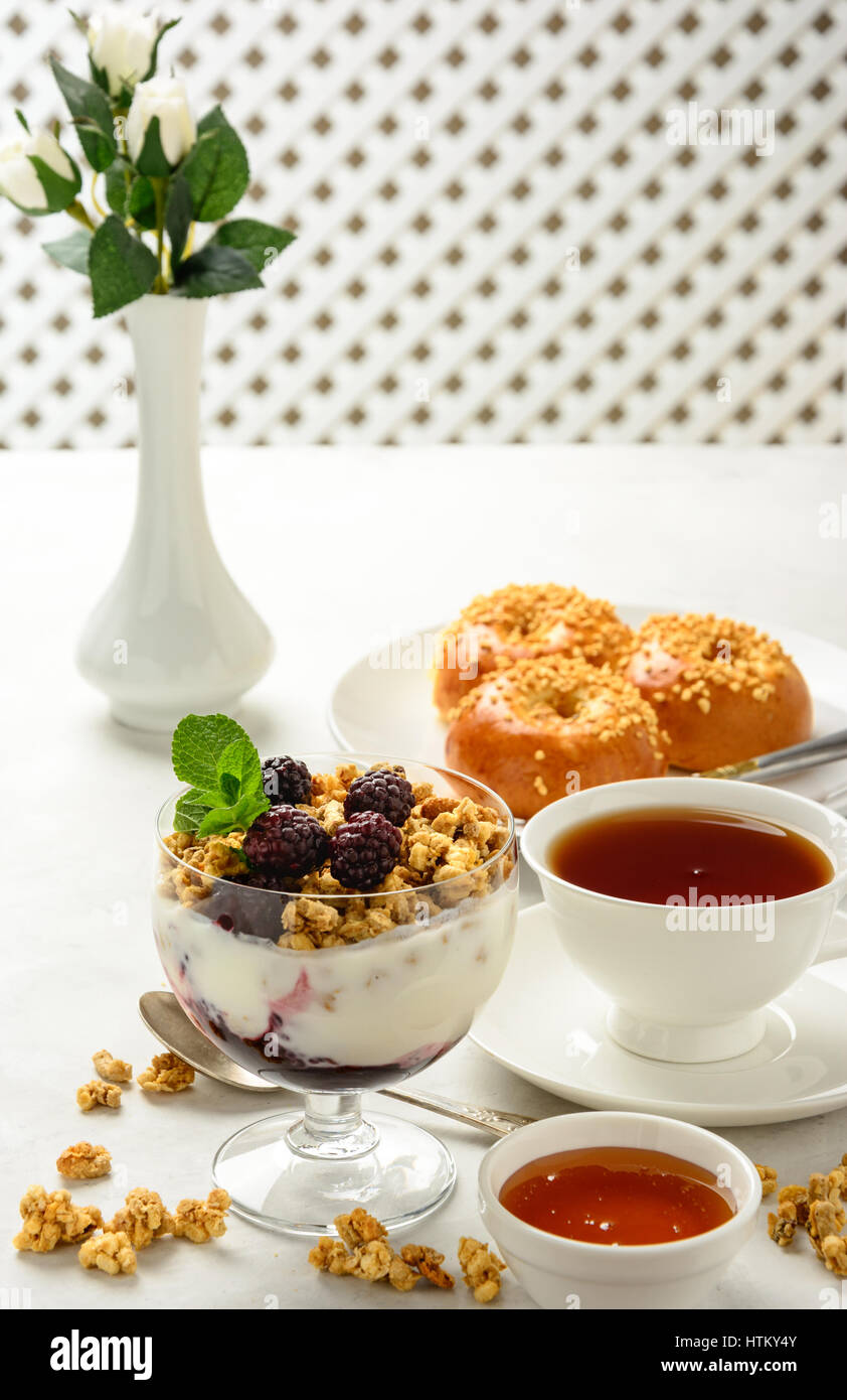 Delicious and healthy breakfast of granola, buns brioche, honey and black tea on a light background. Soft focus. Stock Photo