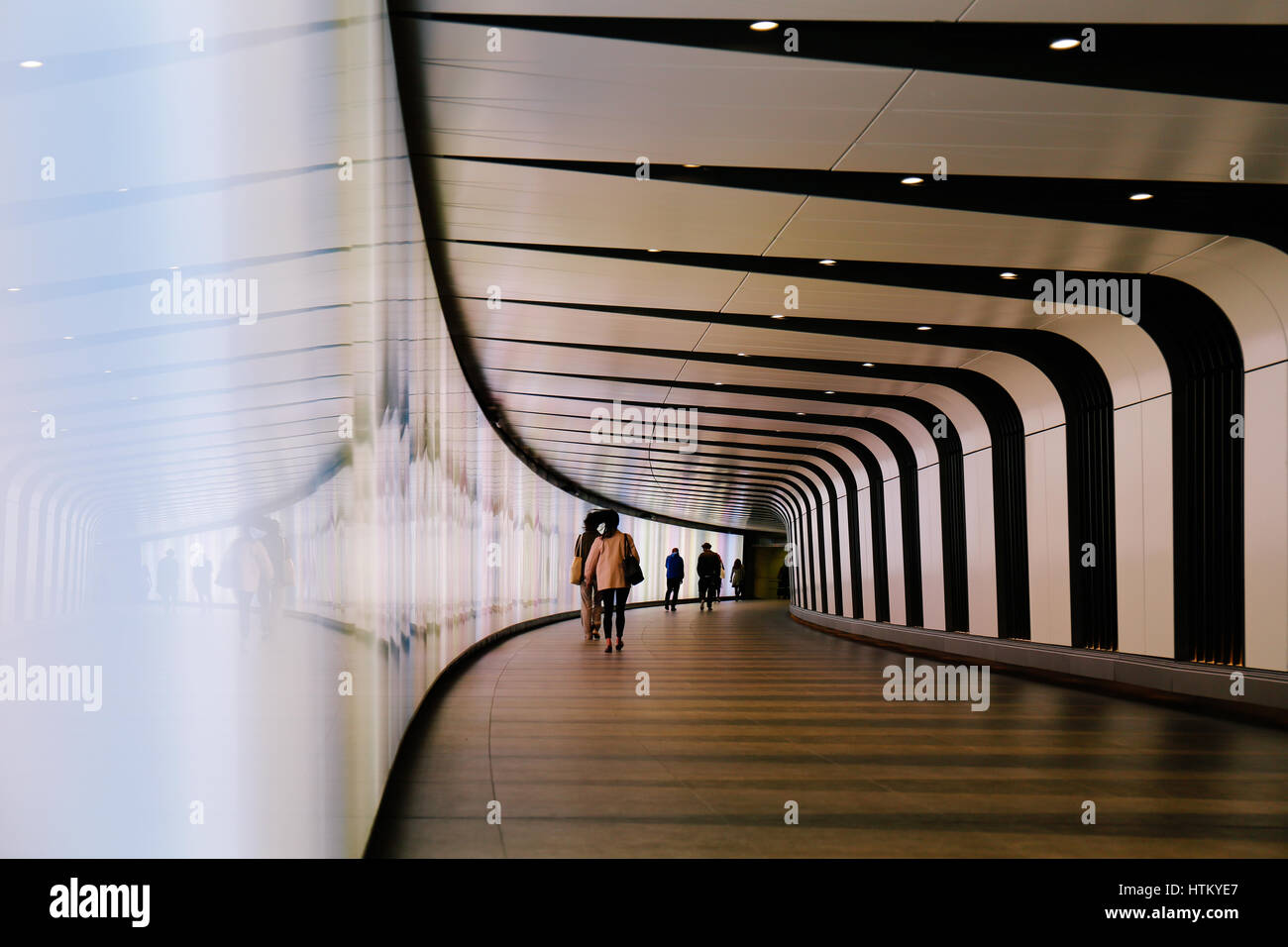 Commutes walking through futuristic looking pedestrian tunnel featuring an LED integrated light wall in Granary Square exit from Kings Cross Undergrou Stock Photo