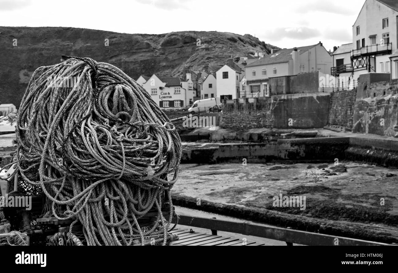 Ropes and Pots along Staithes Harbour looking over towards the famous Cod & Lobster pub. Stock Photo