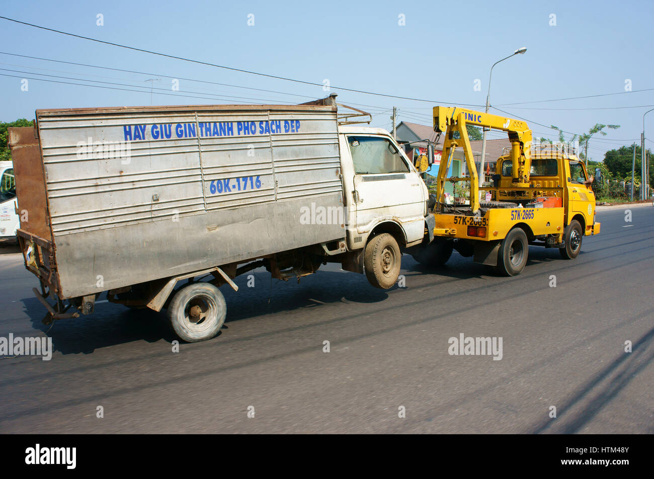 Asian rescue vehicle sercive on street to pull crash truck, yellow crane on car pickup crashed car, accident is very danger for traffic, Vietnam Stock Photo