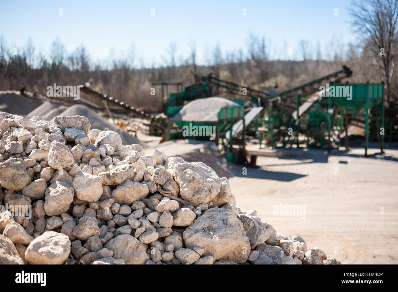 Pile of gravel-rock to be treated. Blurred on background machinery of a gravel pit. Stock Photo