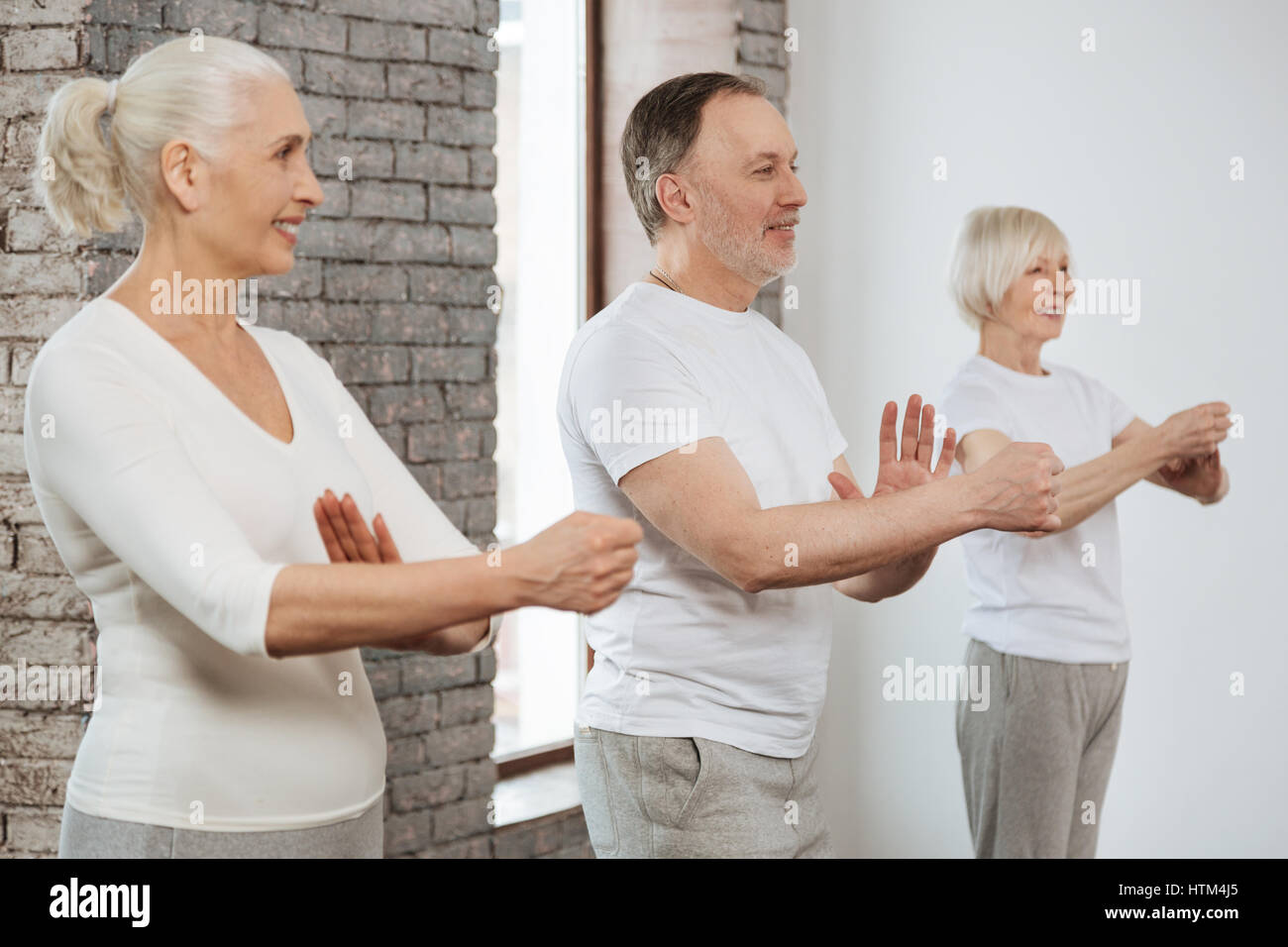 Three elderly people keeping hands in front of themselves Stock Photo