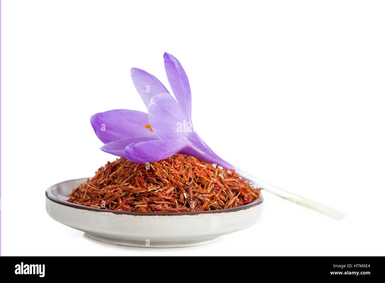 Flower crocus and dried saffron spice in a bowl on white background. Stock Photo