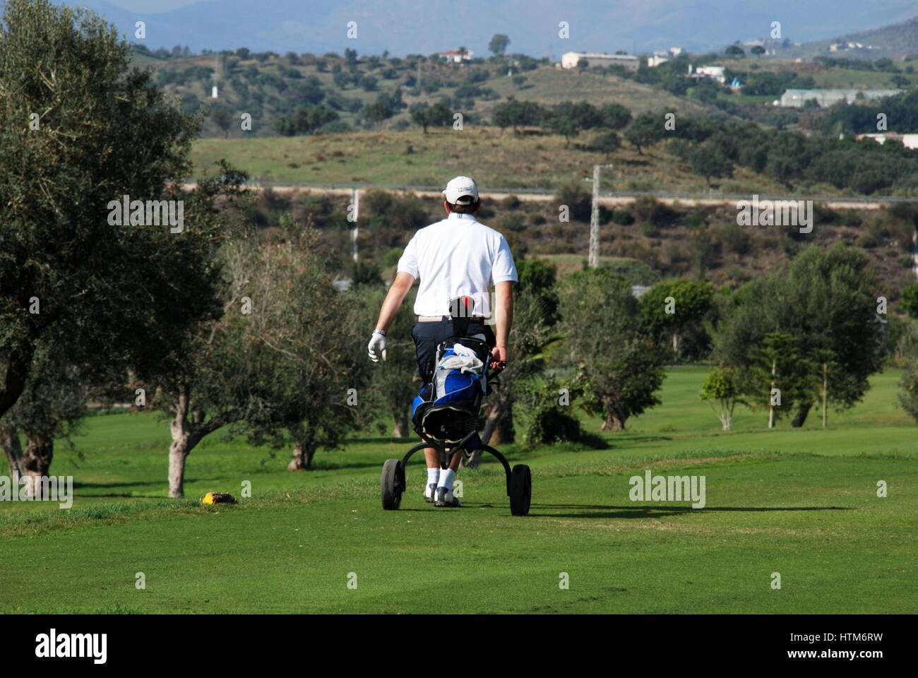 Golfer walking along with his buggy at Los Llanos de Baviera Golf, Caleta de Velez, Malaga Province, Andalusia, Spain, Western Europe. Stock Photo