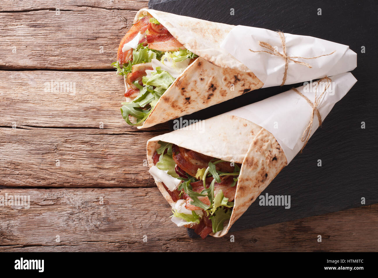 Burritos with bacon and fresh mix of salad close-up on the table. horizontal view from above Stock Photo