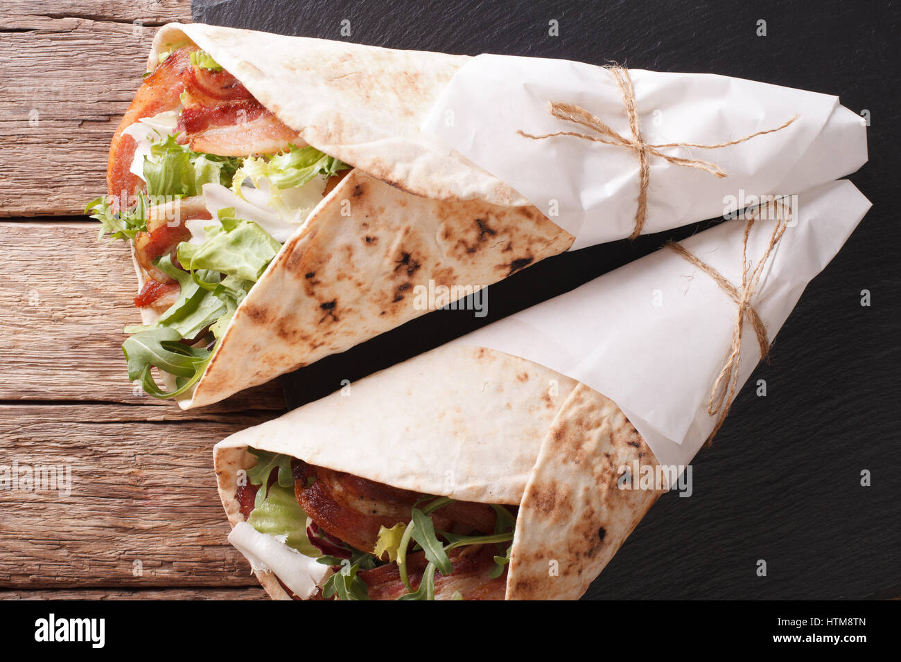 Fried bacon and salad wrapped in pita bread close-up on a table. horizontal view from above Stock Photo