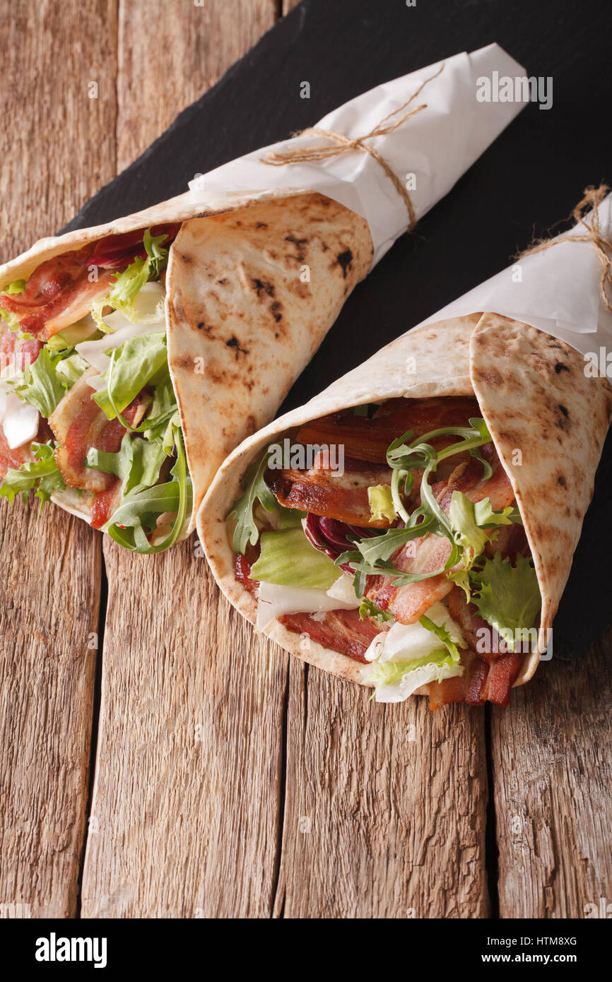 Bacon and lettuce wrapped in pita bread close-up on the table. vertical Stock Photo