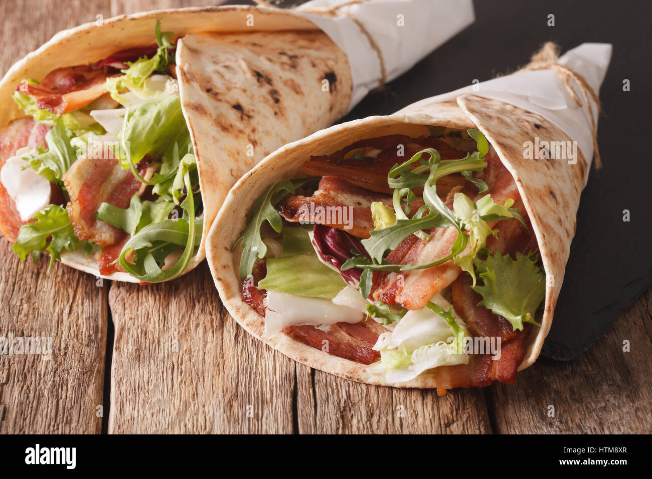 Burritos with bacon and fresh mix of salad close-up on the table. horizontal Stock Photo