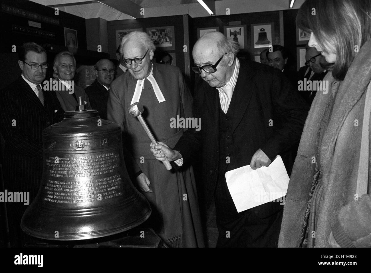The Poet Laureate Sir John Betjeman striking a mounted bell in the Norman Undercroft at Westminster Abbey to officially open the second of the present series of 'miniature' exhibitions being held there. Stock Photo