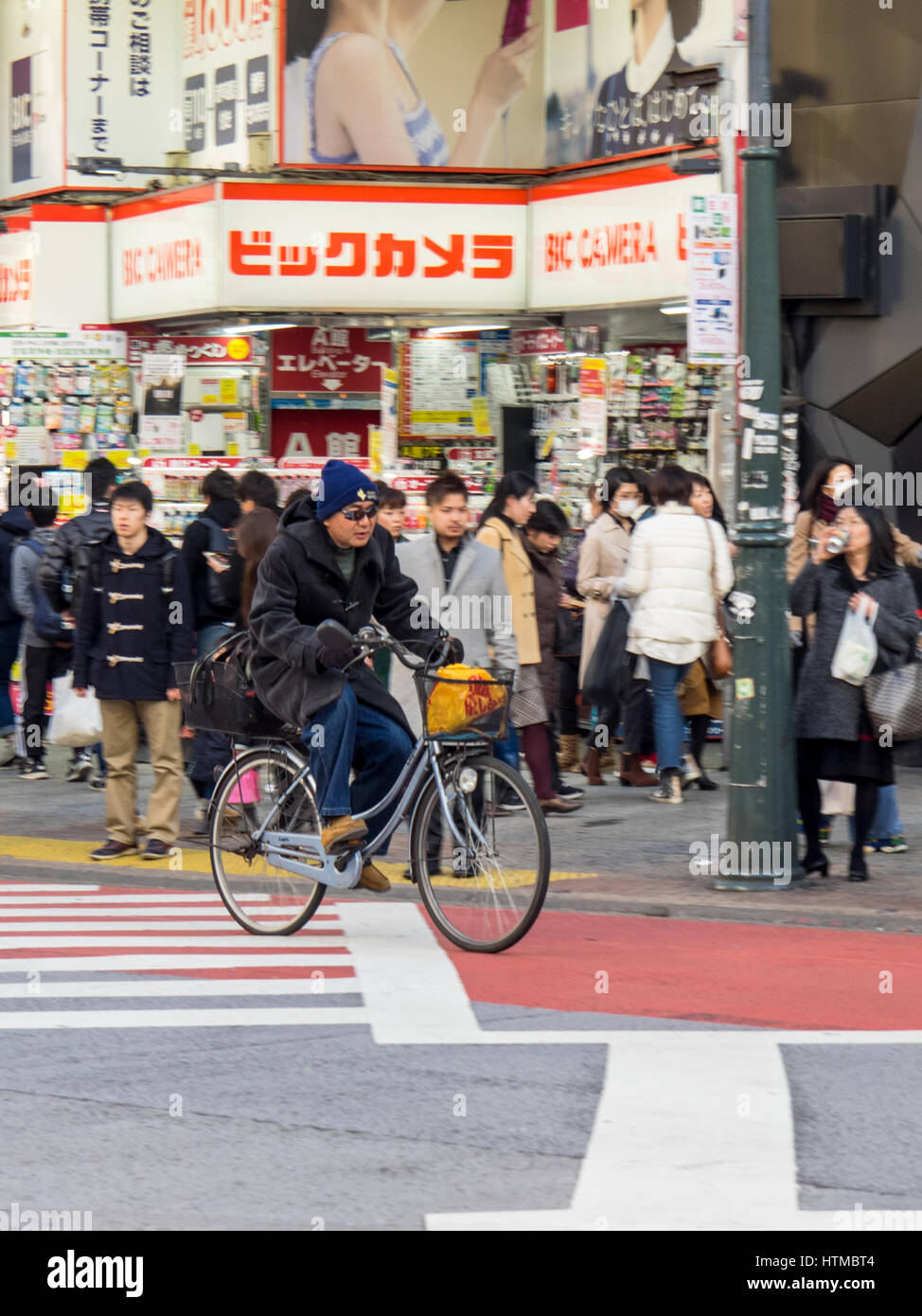 A cyclist cycling across a busy intersection in Shibuya, Tokyo Japan. Stock Photo