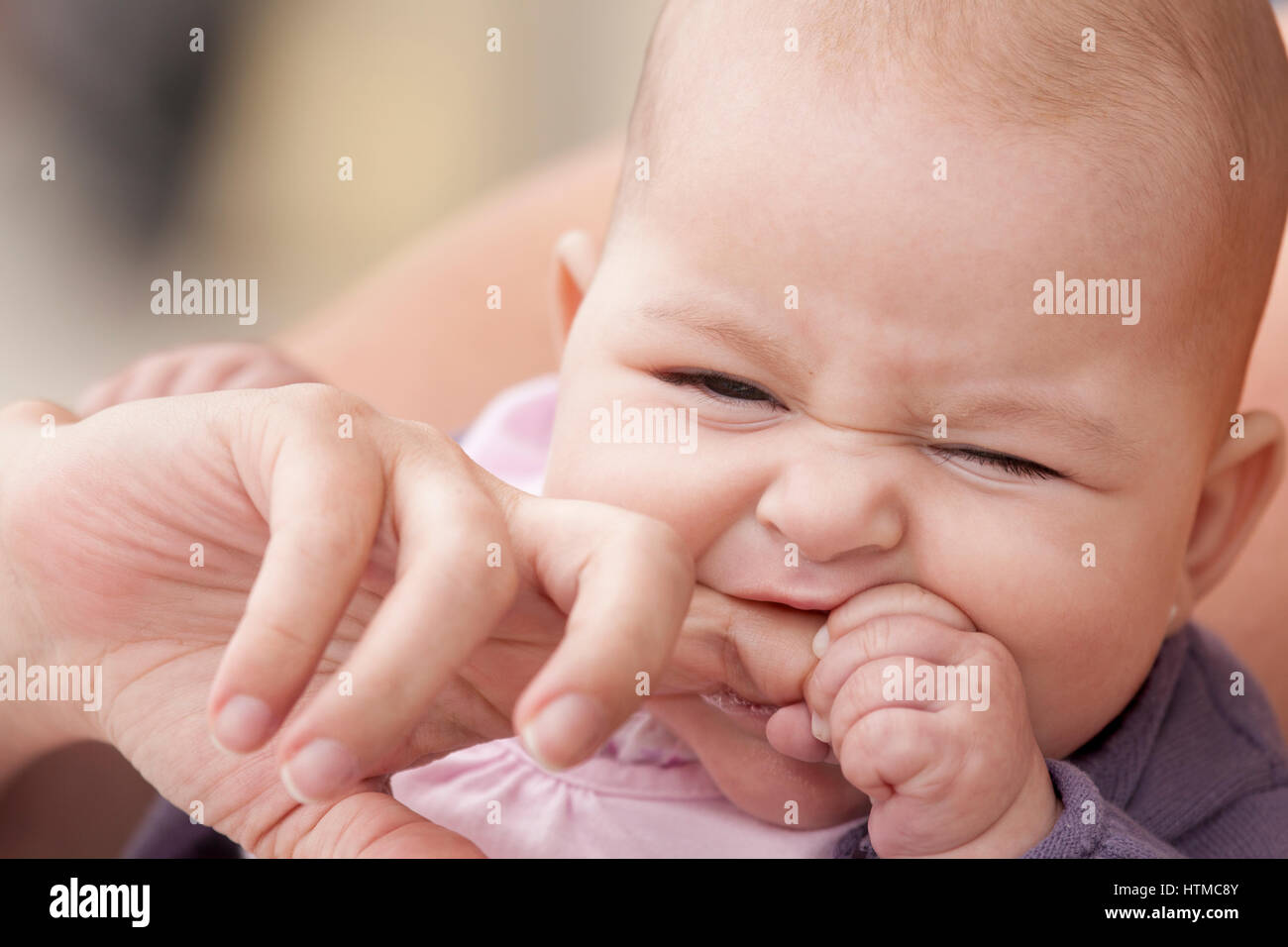 little baby biting her mother finger Stock Photo