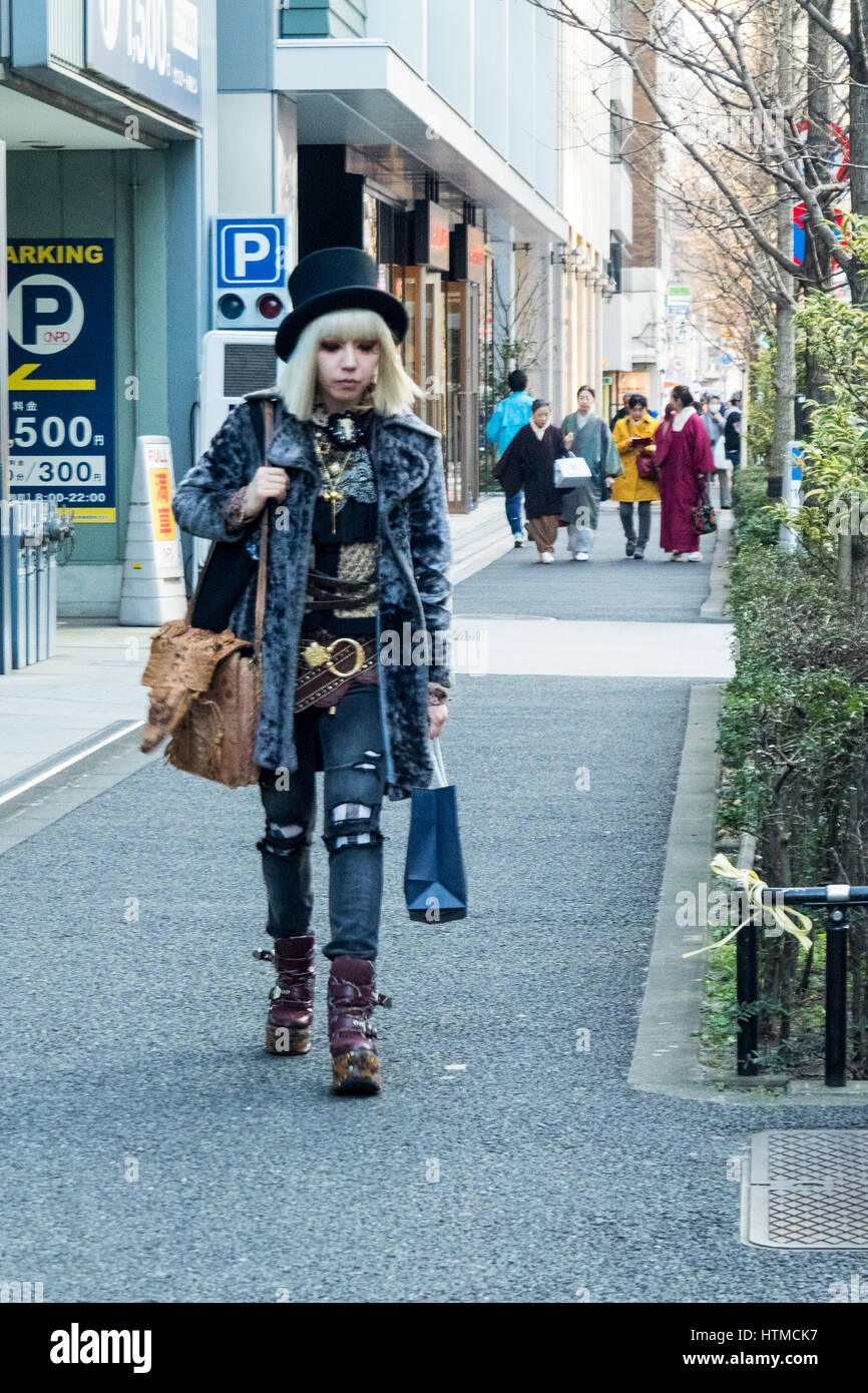 Japanese woman with blonde hair dressed in cut denim and in contrast older women in traditional wear walking behind her, Shibuya Tokyo Japan. Stock Photo