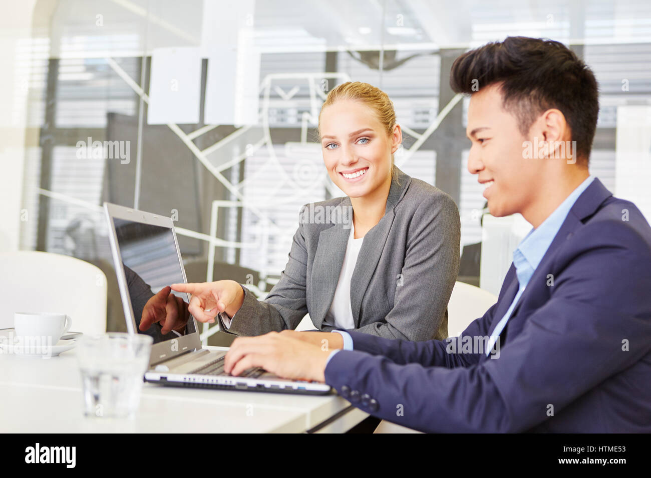 Two business people at computer seminar using laptop in the office Stock Photo