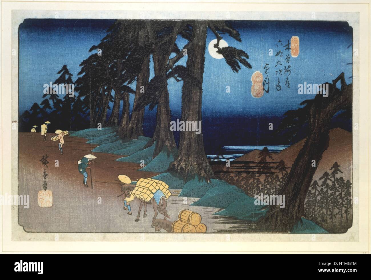 Mochizuki: Full Moon. From 'The Sixty-nine Stations of the Kisokaido Road' 1832-1834. Coloured woodblock print. Porters and pack animals transport goods along a road lined with pine trees. Ando Hiroshige also called Ando Tokutaro (1797-1858) Japanese artist and printmaker. Stock Photo