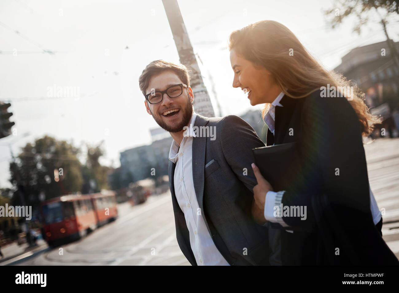 Happy business people walking in city and smiling Stock Photo - Alamy