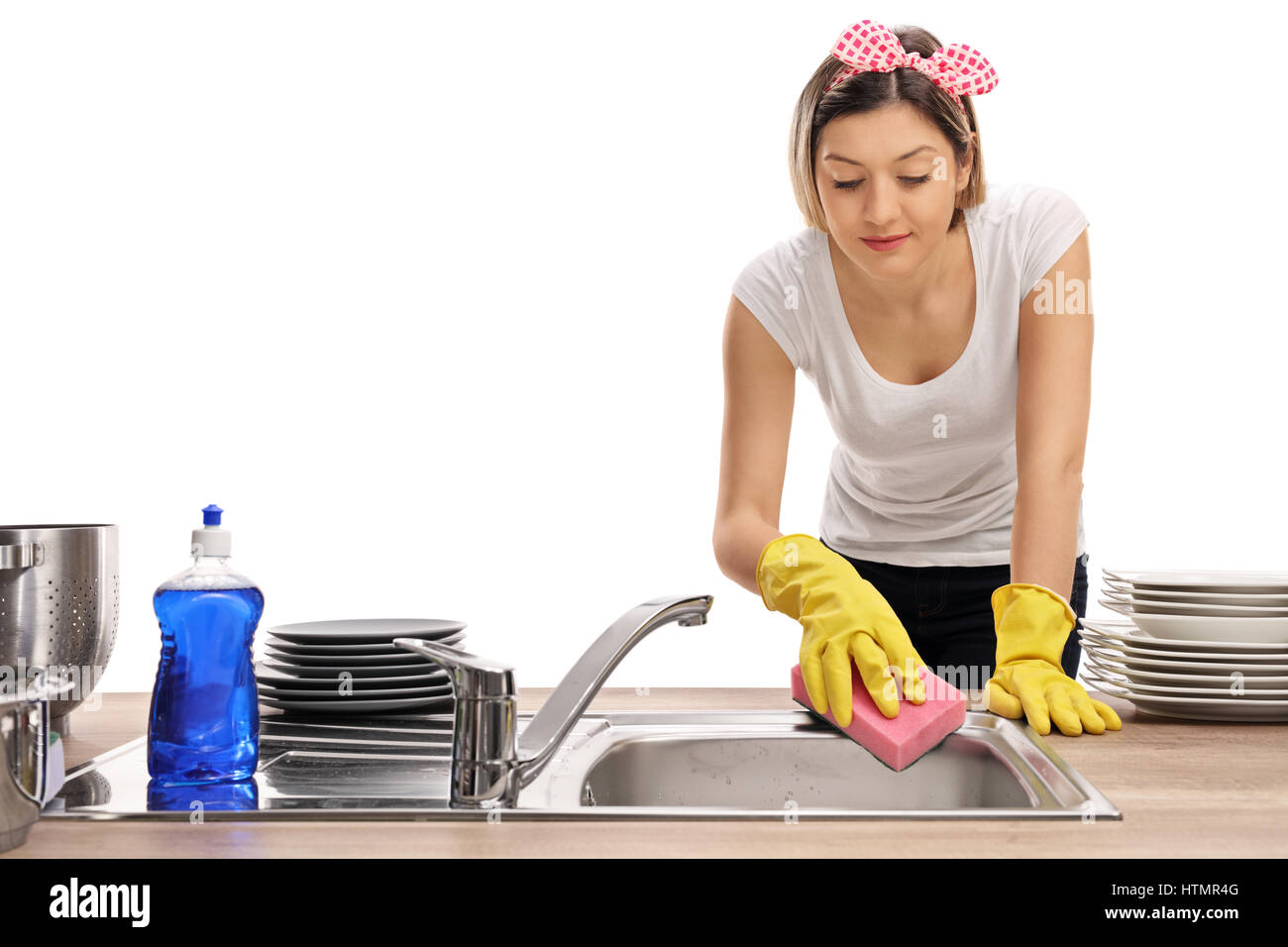 Young woman cleaning a sink with a sponge isolated on white background Stock Photo