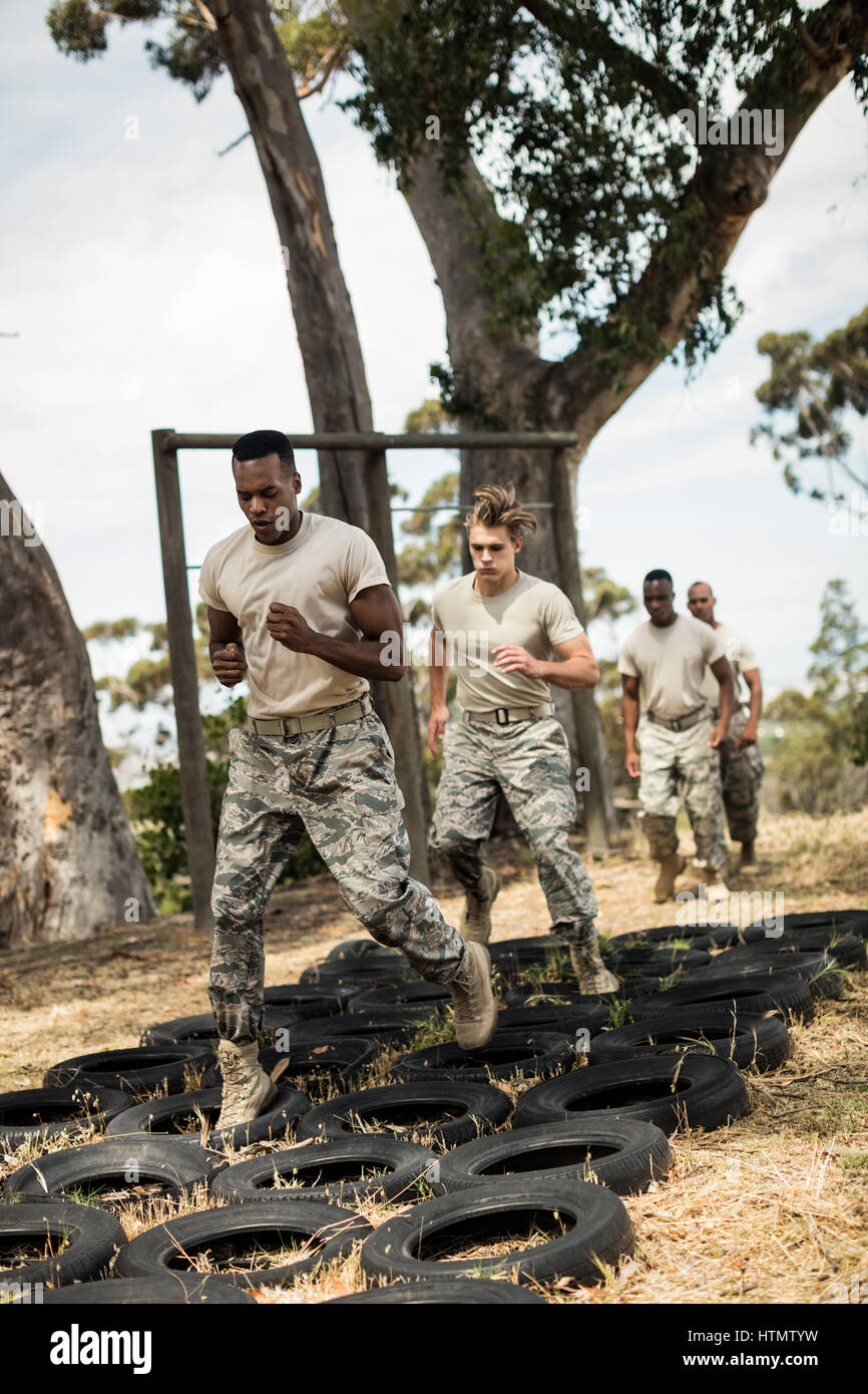 Young military soldiers practicing tyre obstacle course at boot camp Stock Photo